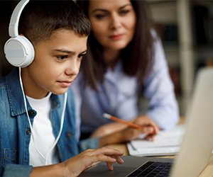 Child doing homework online with parent nearby