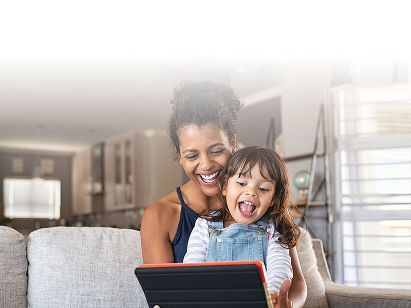 smiling adult and child playing on tablet