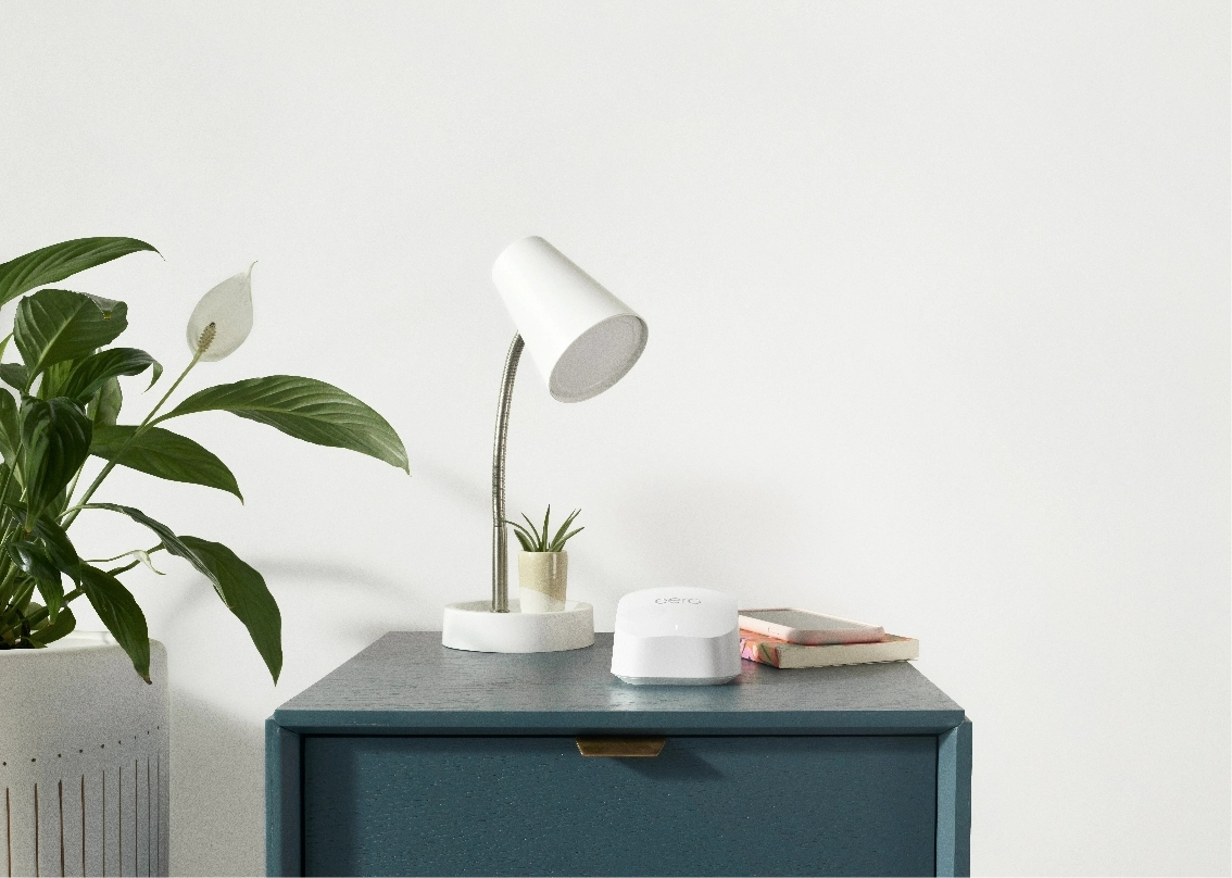 the wall to wall wifi device placed on a small table along with a lamp a succulent and a book 