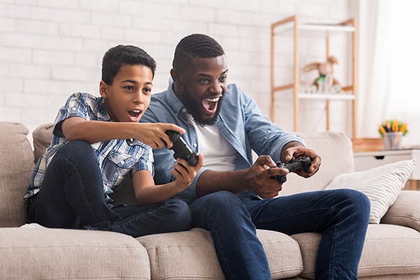 parent and child having a great time playing video games on a couch